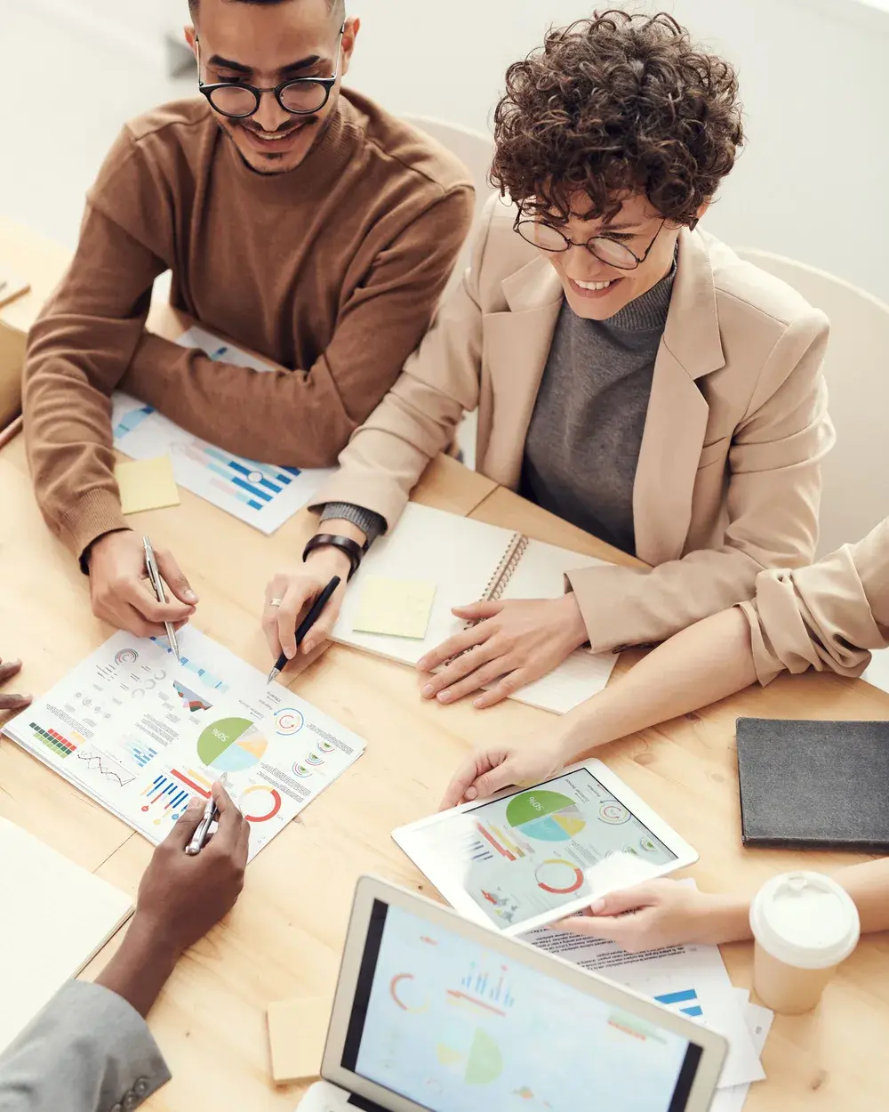 Trois collègues analysent ensemble des tableaux de bord et des graphiques autour d'une table de réunion.